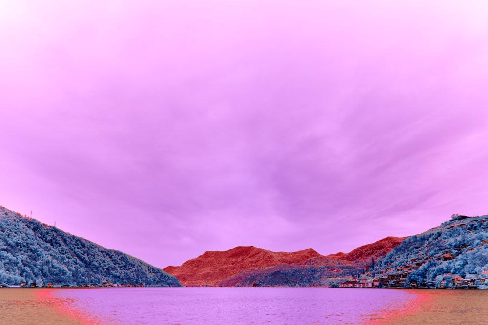 a purple sky over a lake with mountains in the background