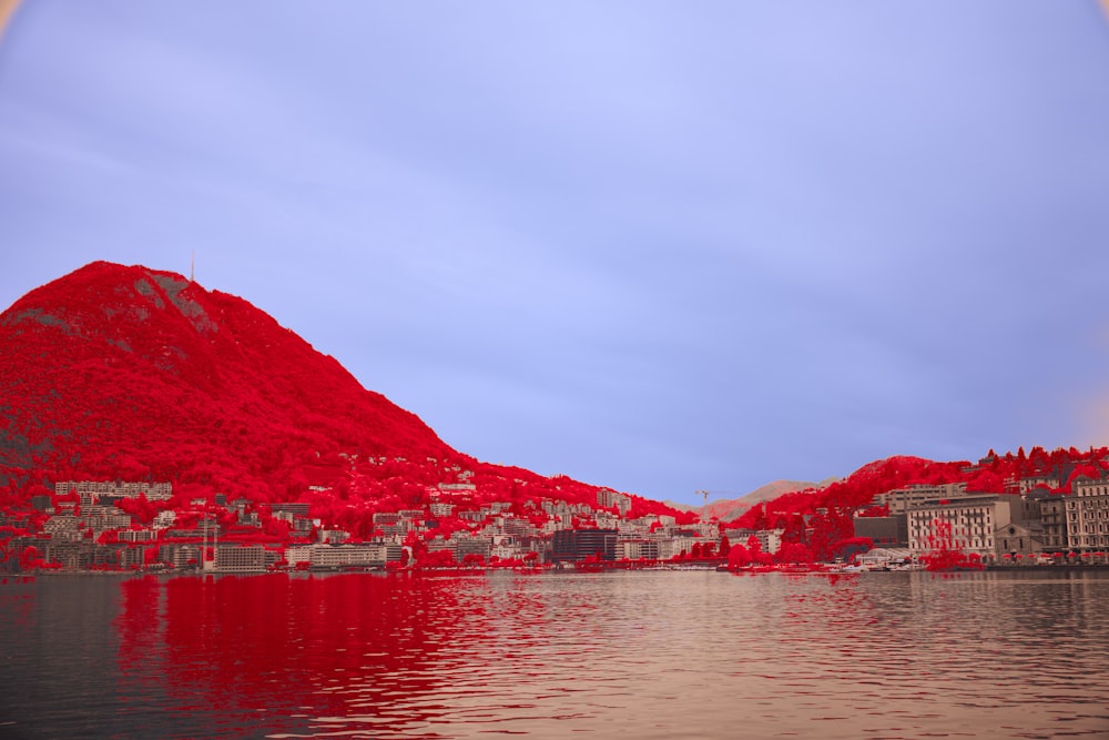 a large body of water with a red mountain in the background