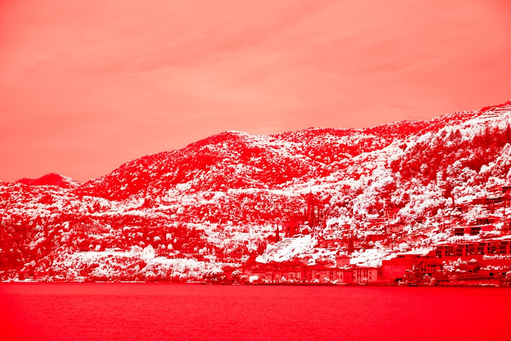 a mountain covered in snow next to a body of water