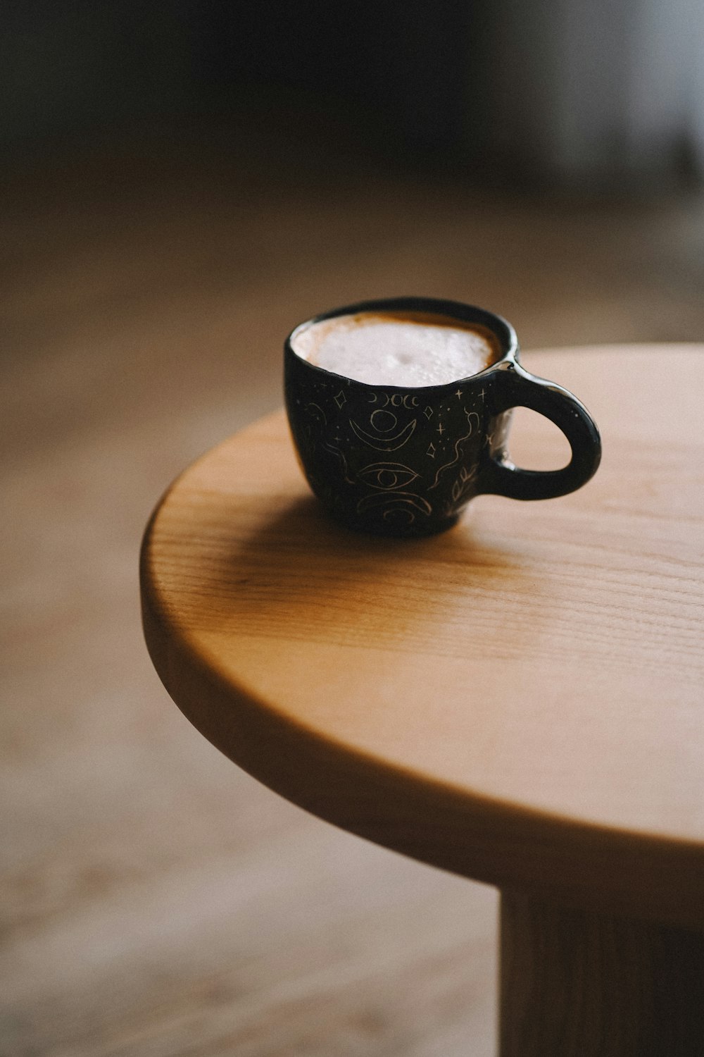 a cup of coffee sitting on top of a wooden table