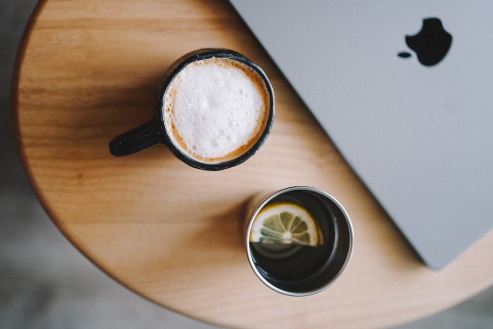 a cup of coffee next to a laptop on a table