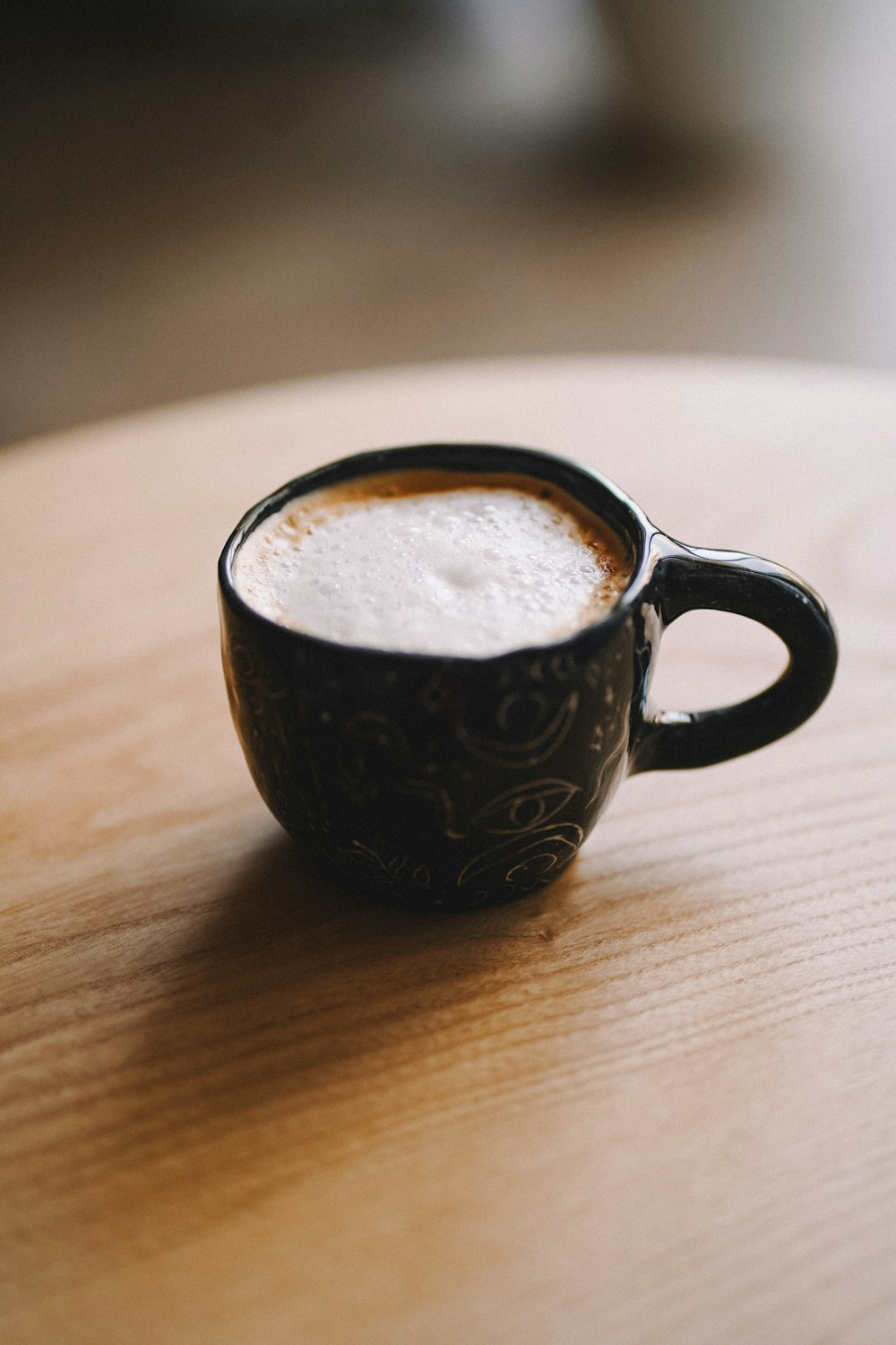 a cup of coffee sitting on top of a wooden table