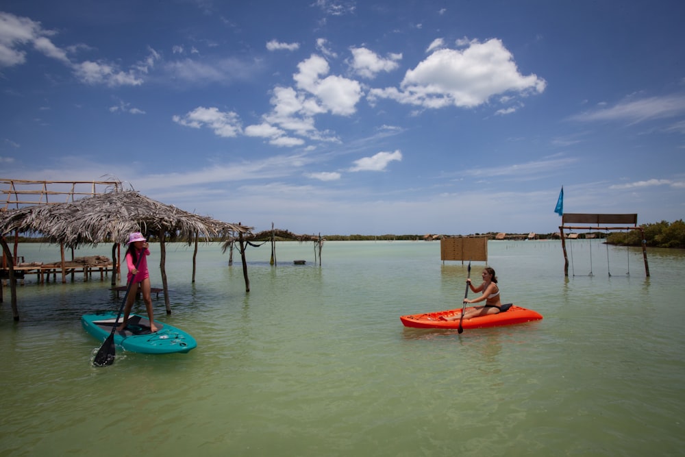 a couple of people riding on top of kayaks in the water