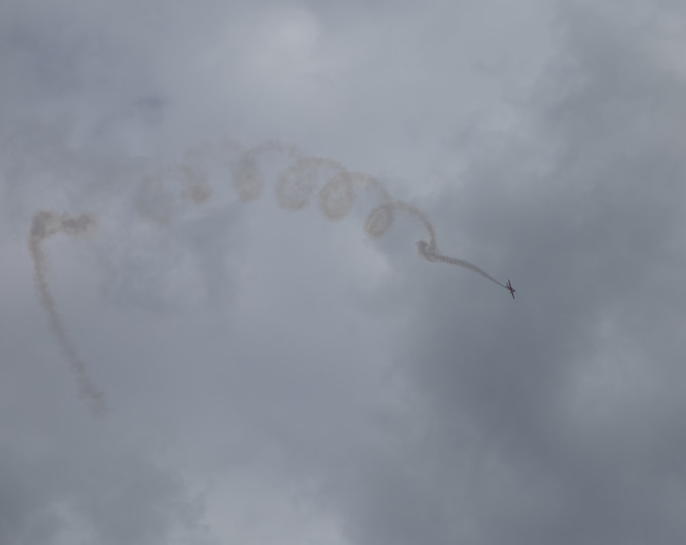 a jet flying through a cloudy sky with smoke coming out of it