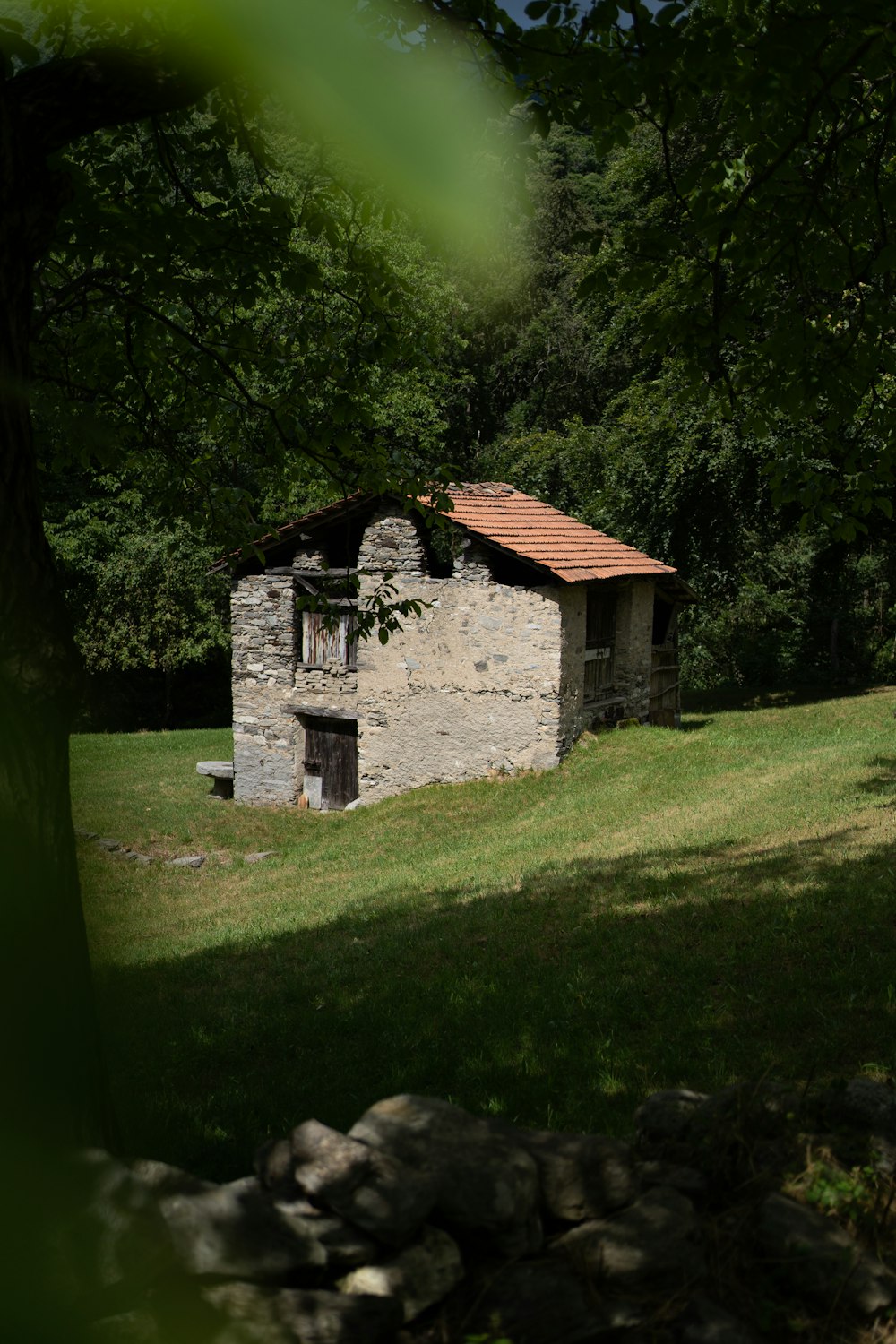 a small stone building sitting in the middle of a field