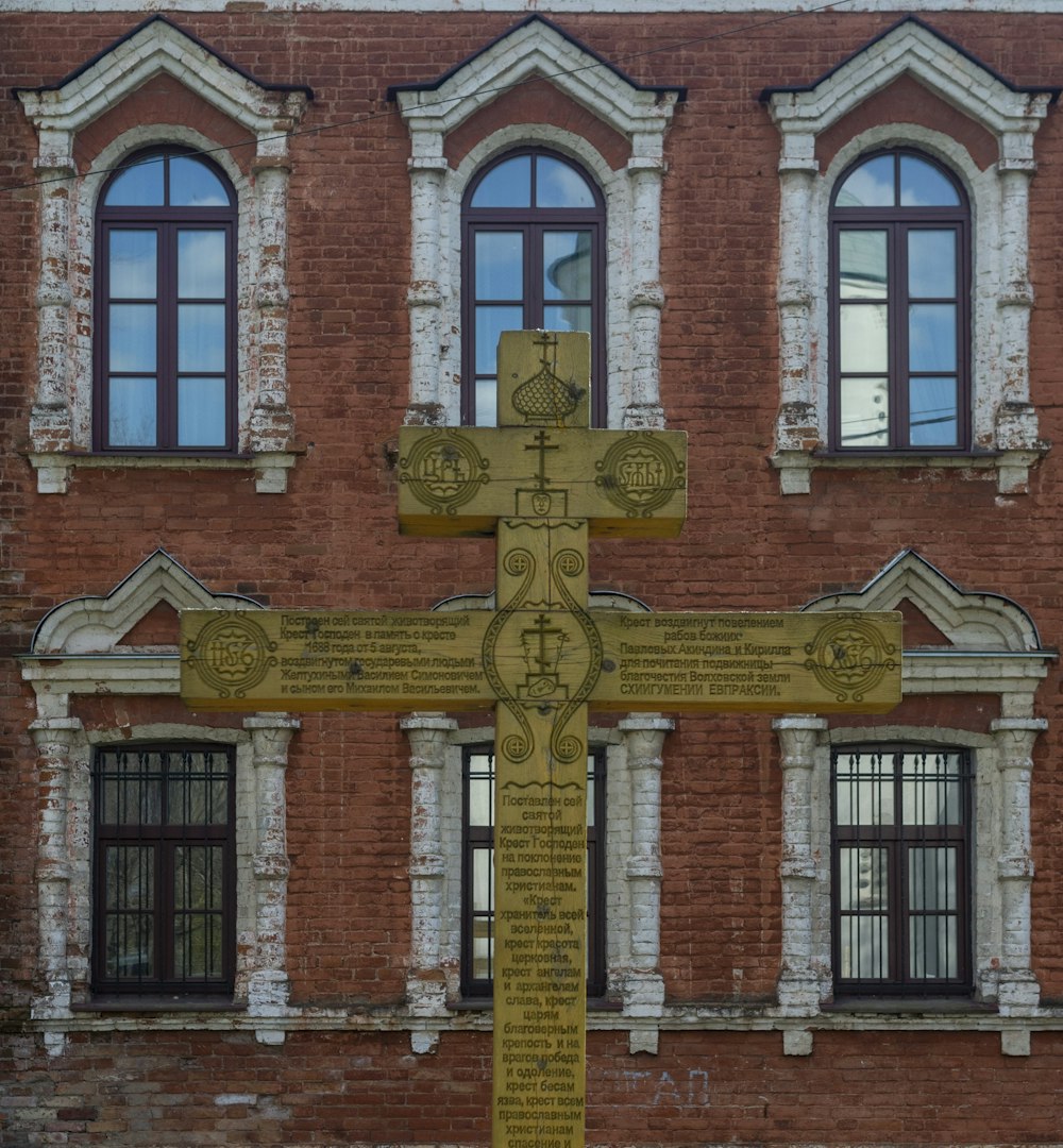 una grande croce gialla seduta di fronte a un edificio di mattoni