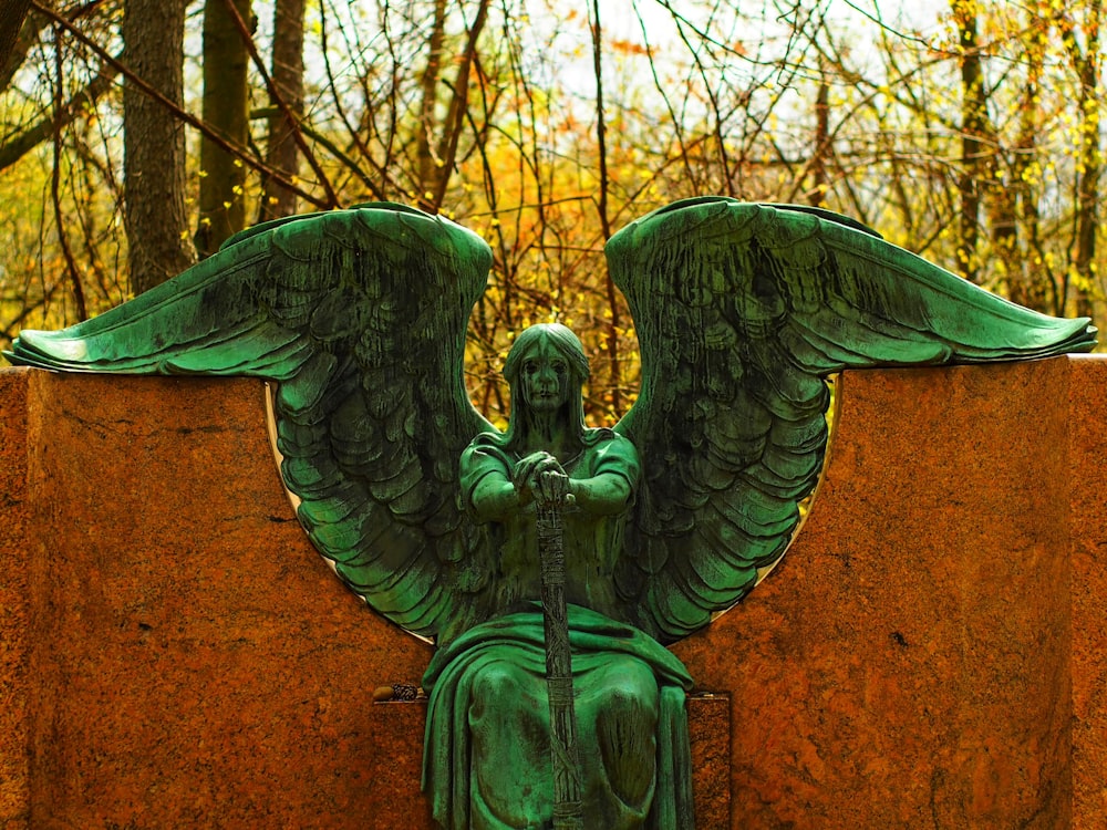 une statue d’un ange assis au sommet d’un mur de pierre