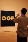a man taking a picture of a logo on a wall