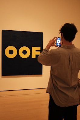 a man taking a picture of a logo on a wall