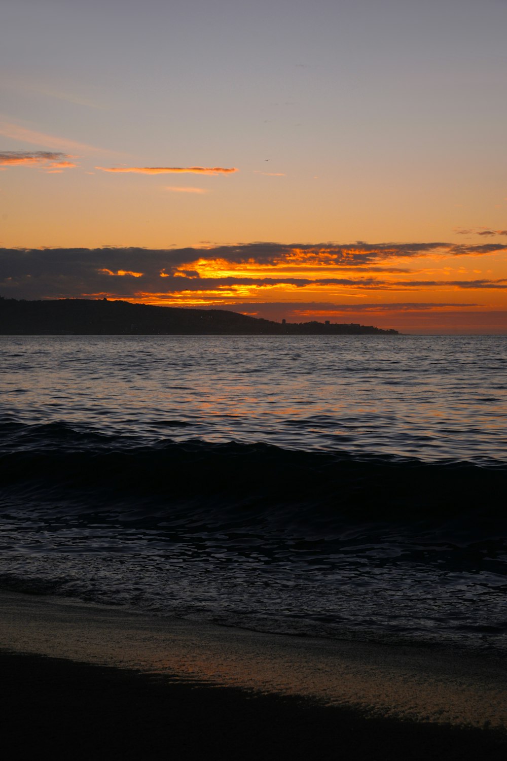 the sun is setting over the water at the beach