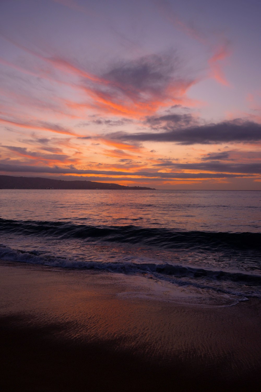 a sunset over the ocean with waves coming in