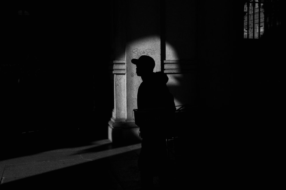 a person standing in a dark room next to a window