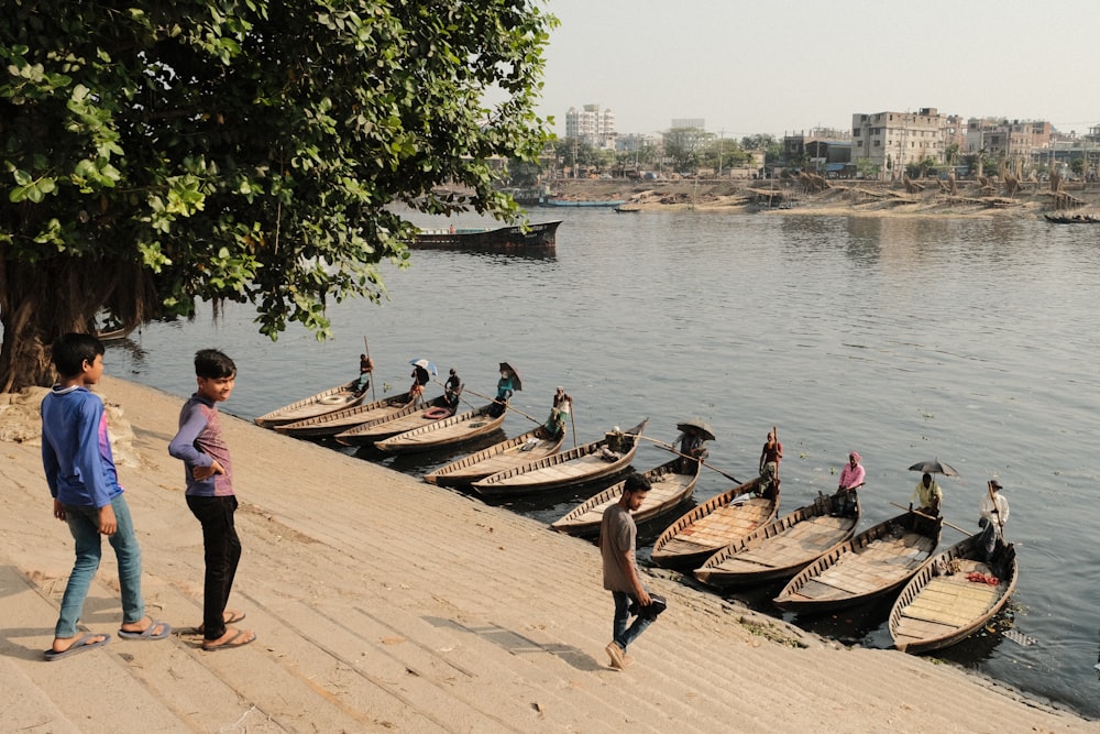 a group of people standing next to a bunch of boats