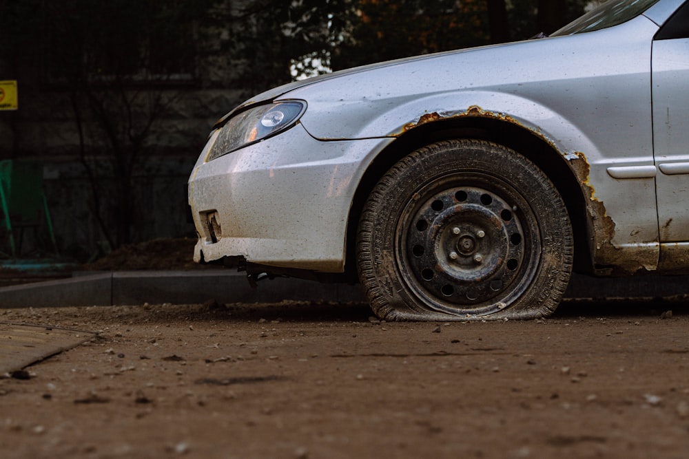 a dirty white car parked on the side of the road