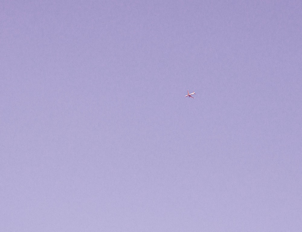 a plane flying in the sky with a purple background