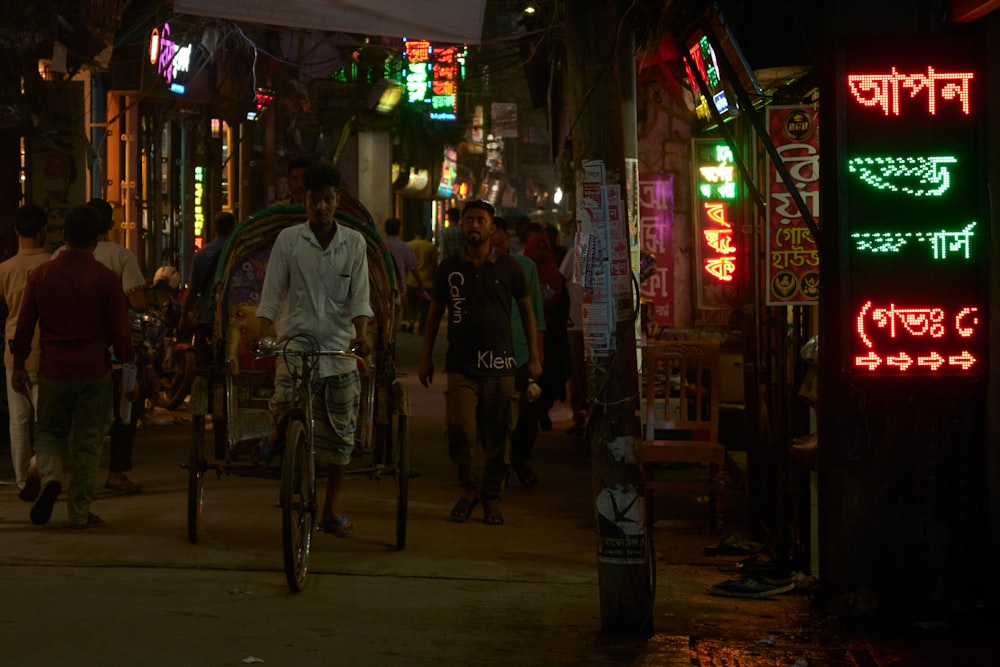 a man riding a bike down a street at night