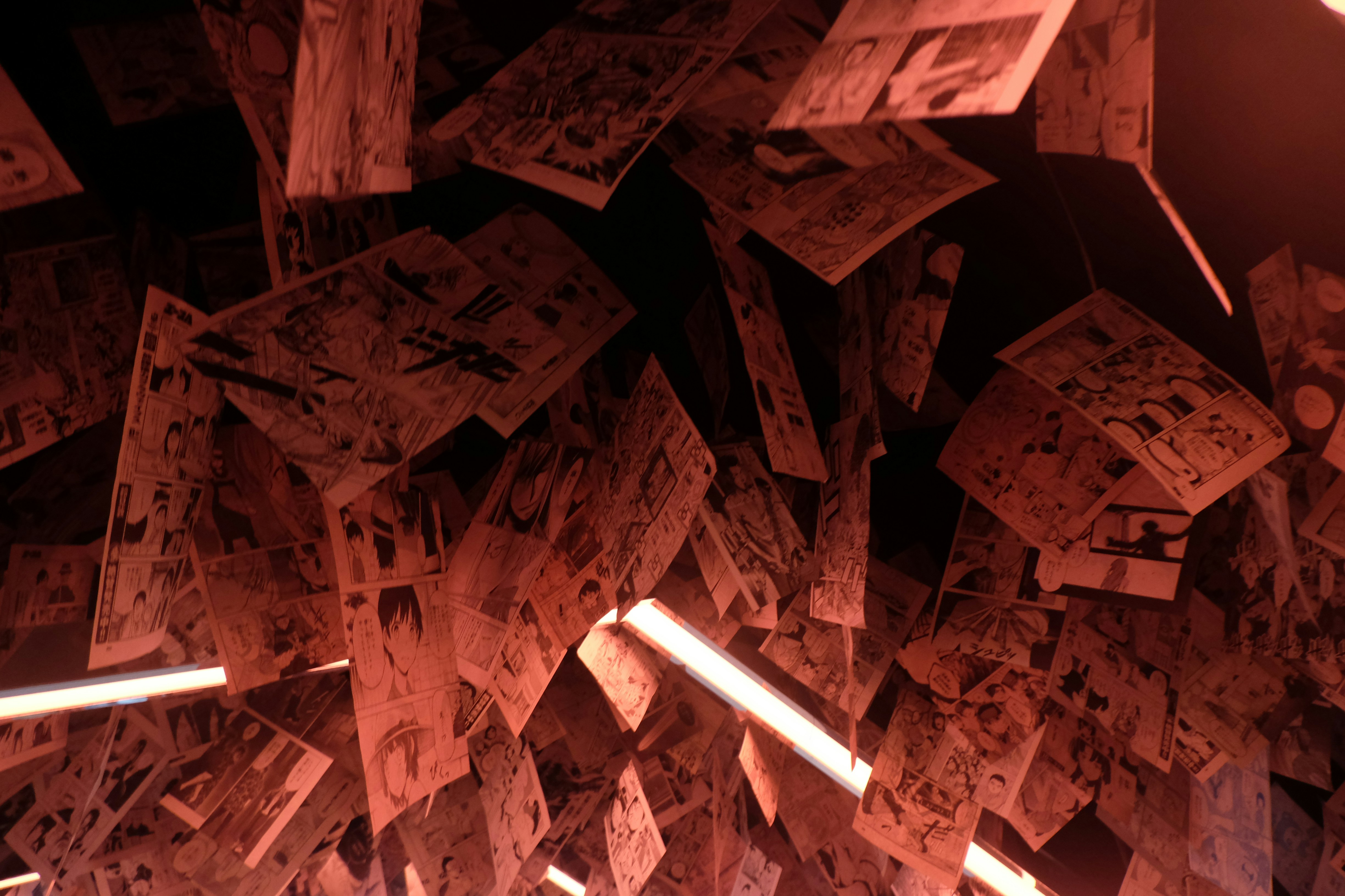 Vibrant anime artwork illuminated by warm amber LED light in a dark display room, deep shadows