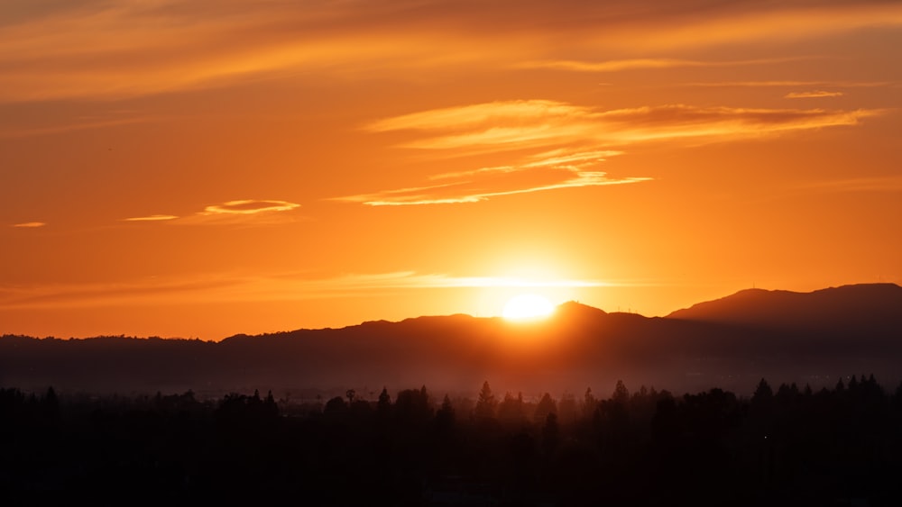 the sun is setting over a mountain range