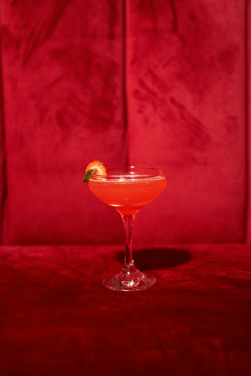 a cocktail sitting on top of a table next to a red wall