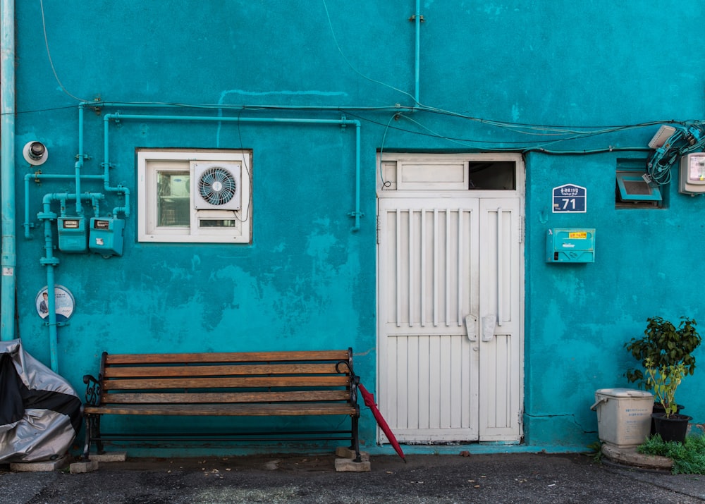 a wooden bench sitting in front of a blue building