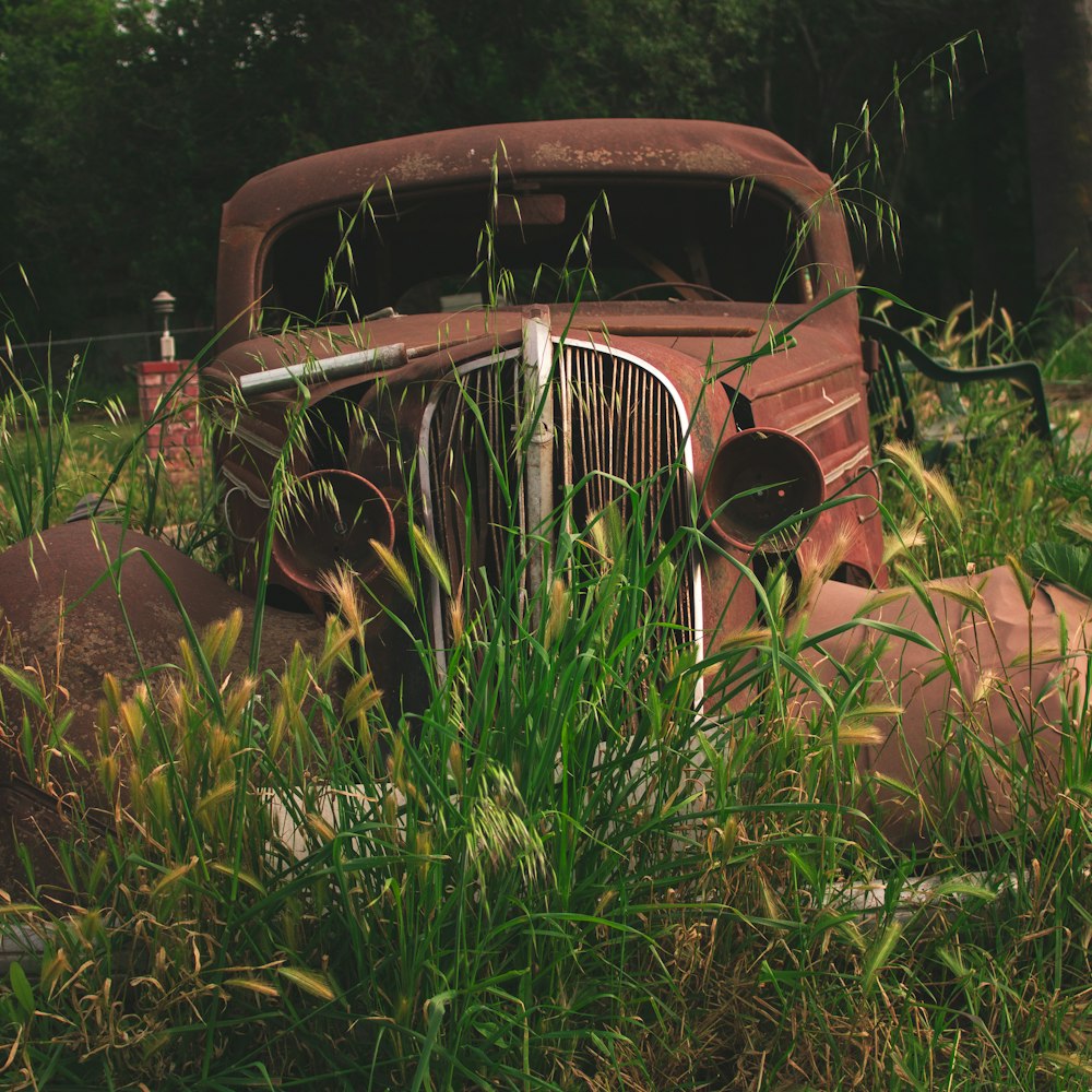 an old rusted truck sitting in a field of tall grass