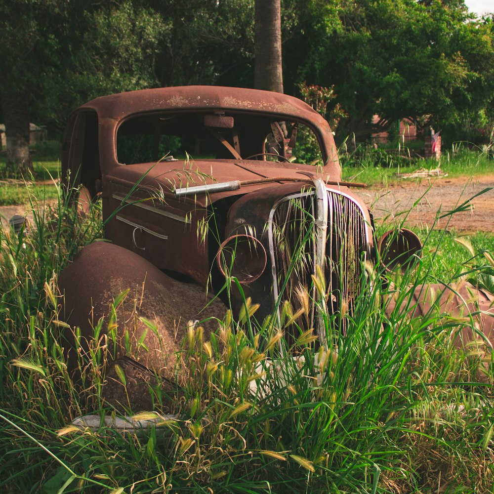 an old rusted truck sitting in a field of tall grass