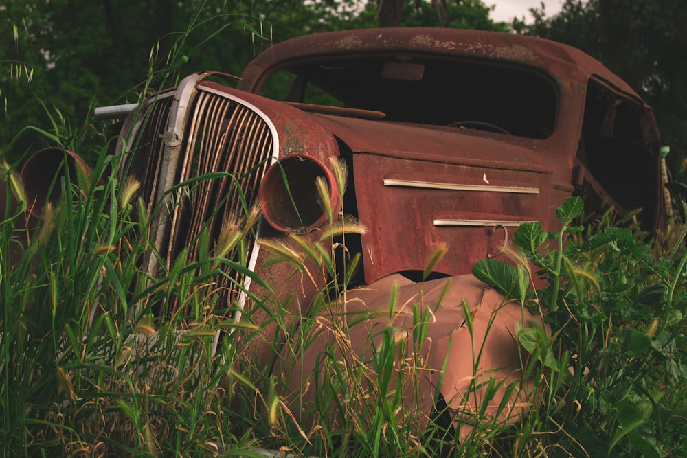 an old truck sitting in a field of tall grass