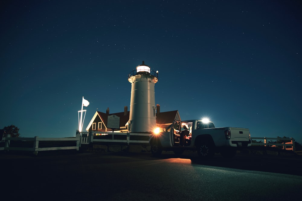 a truck parked in front of a lighthouse at night