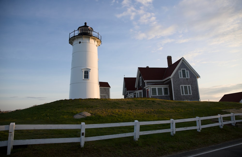 a lighthouse on top of a hill with a house in the background
