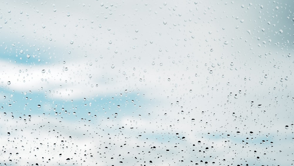 rain drops on a window with a cloudy sky in the background