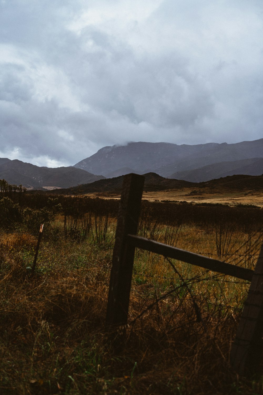 a fence in a field with mountains in the background