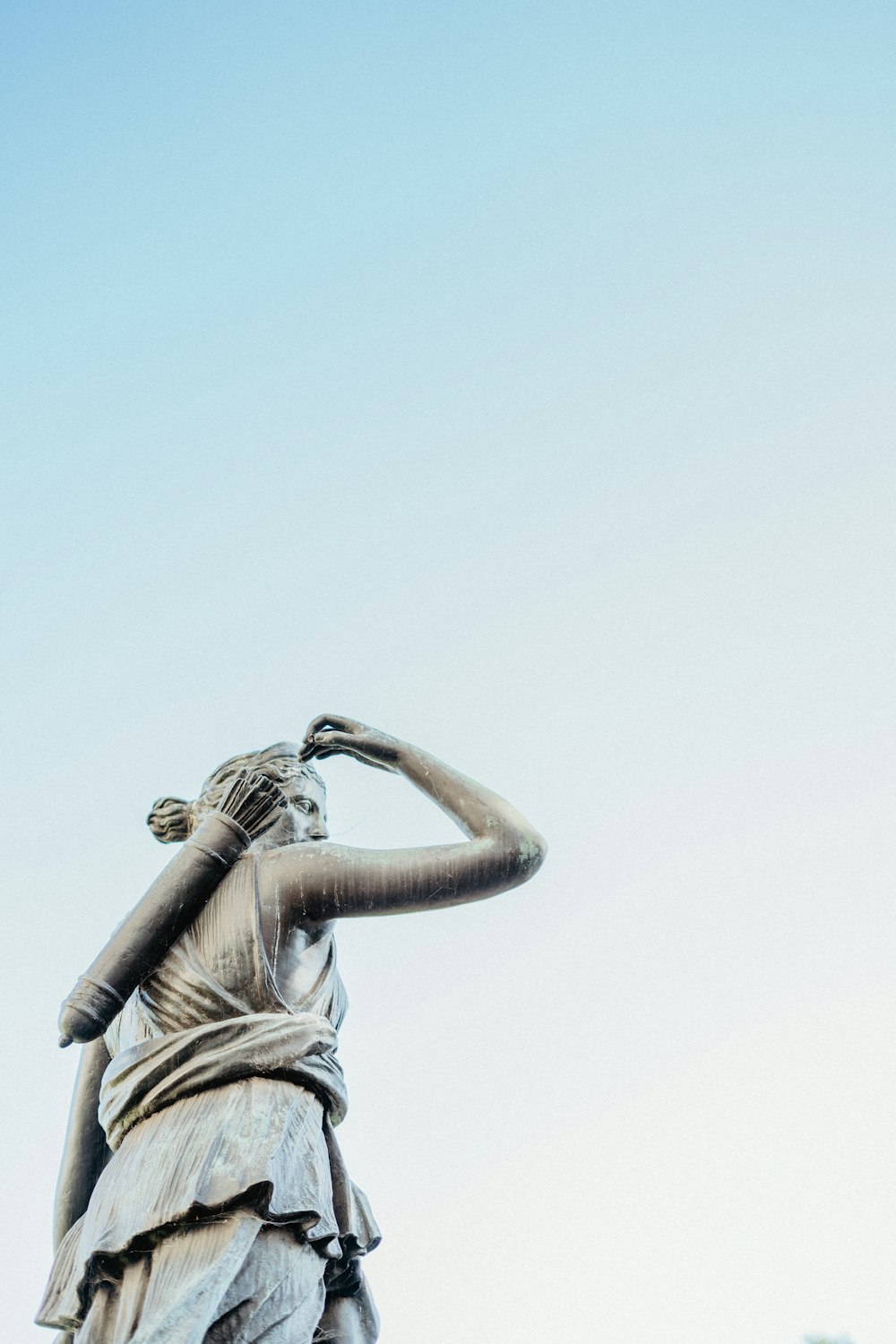 une statue d’une femme tenant ses mains sur sa tête