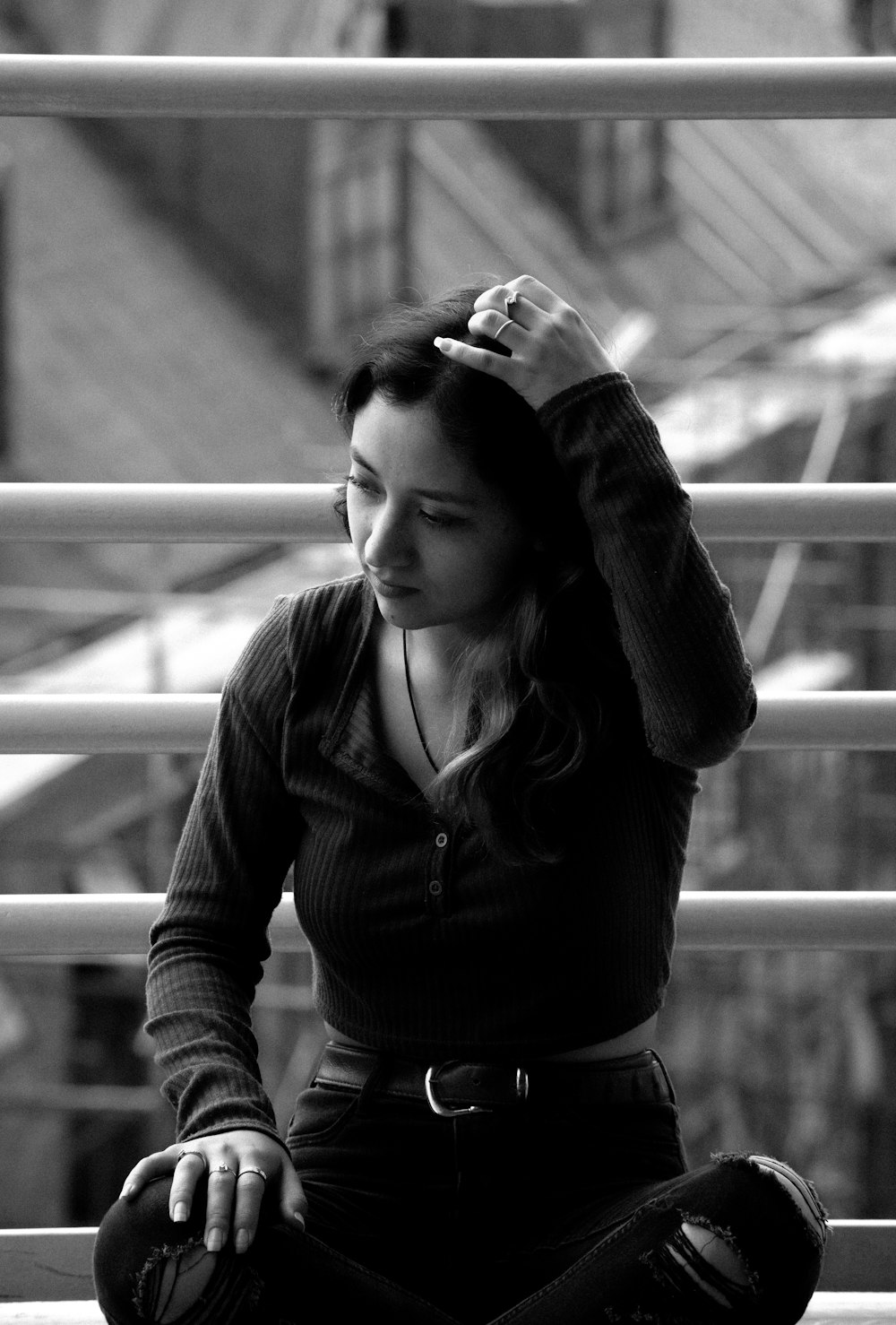 a woman sitting on a ledge with her hands on her head