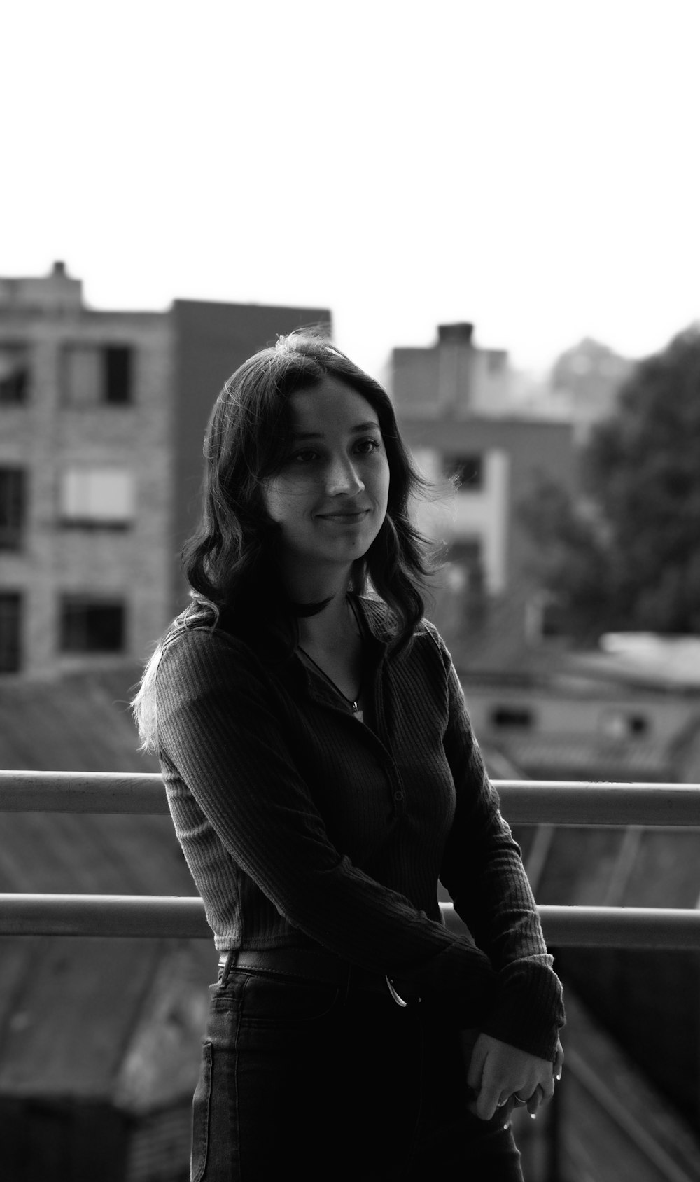 a black and white photo of a woman standing on a balcony