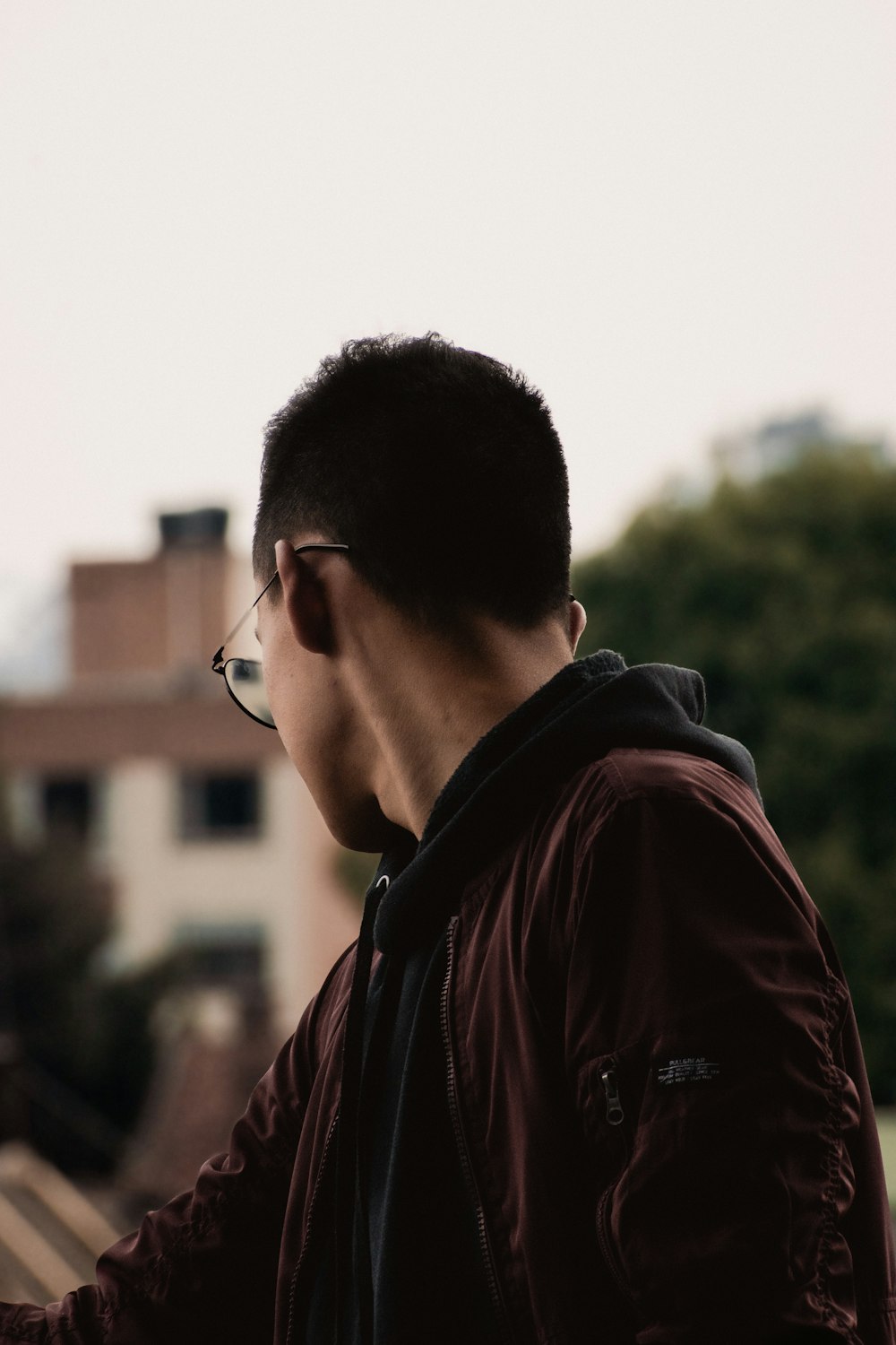 a man in a maroon jacket and glasses looking at something