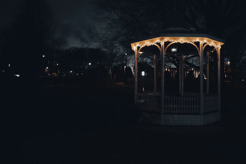 Lit-up gazebo in a park at night with string lights