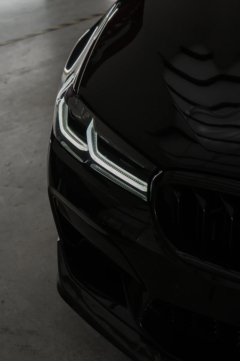 Close-up of a black car's front end showing a deep, ceramic-coated gloss