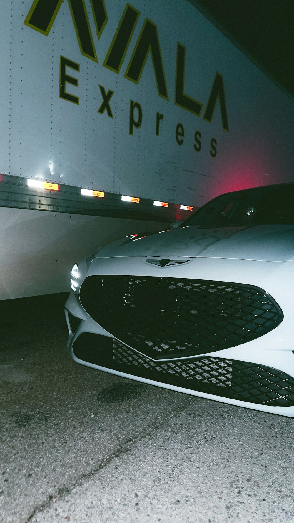 a white car parked in front of a truck