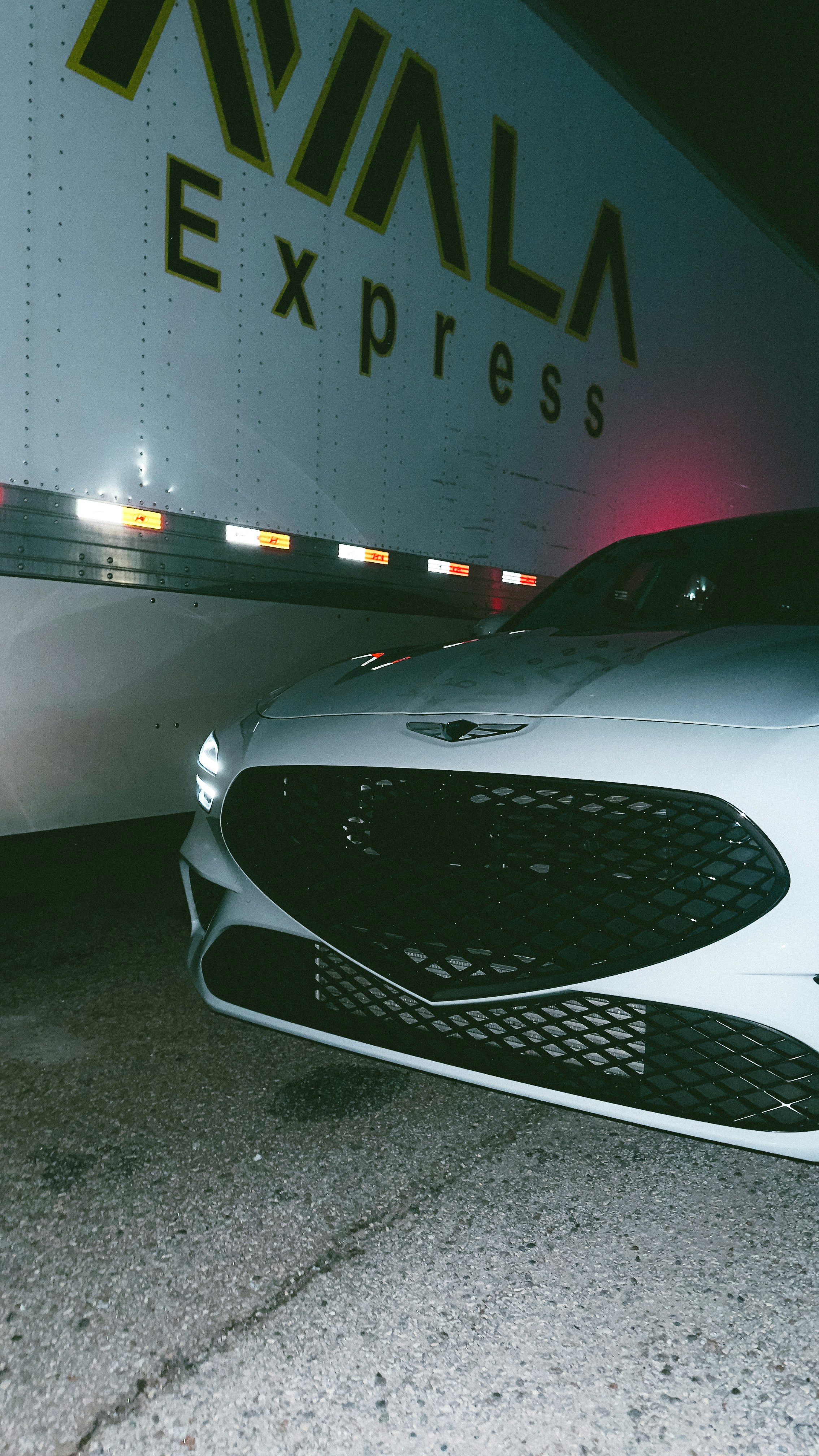 a white car parked in front of a truck