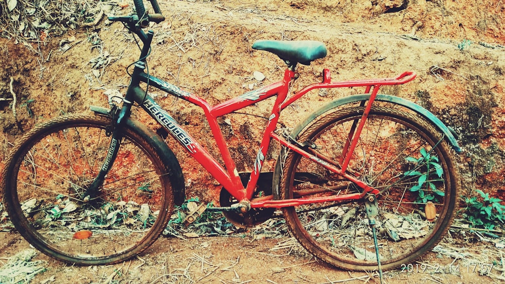 a red bike parked next to a rock wall