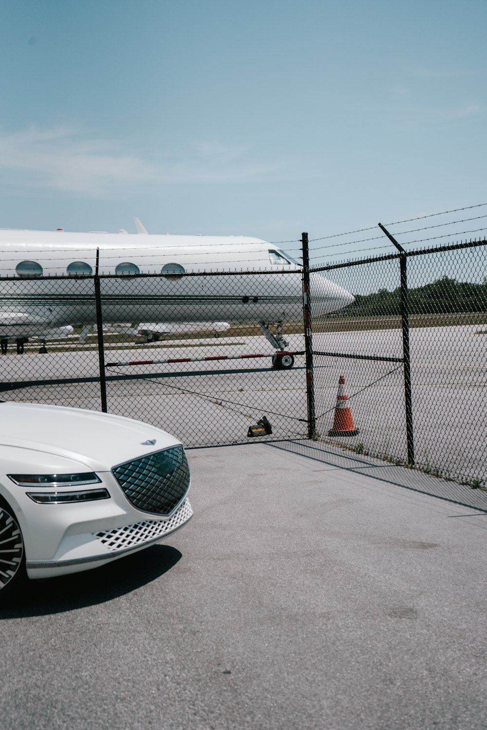 a white car is parked in front of a fence