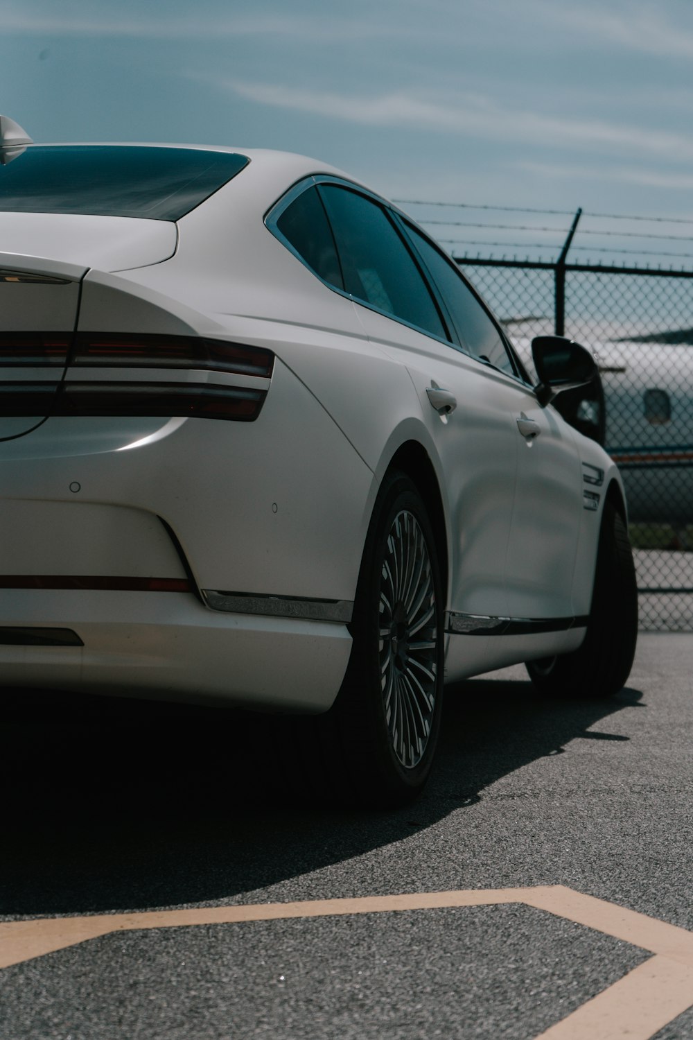 a white car parked in a parking lot next to a fence