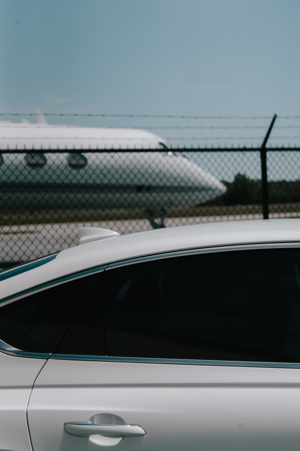 a white car parked in front of a fence