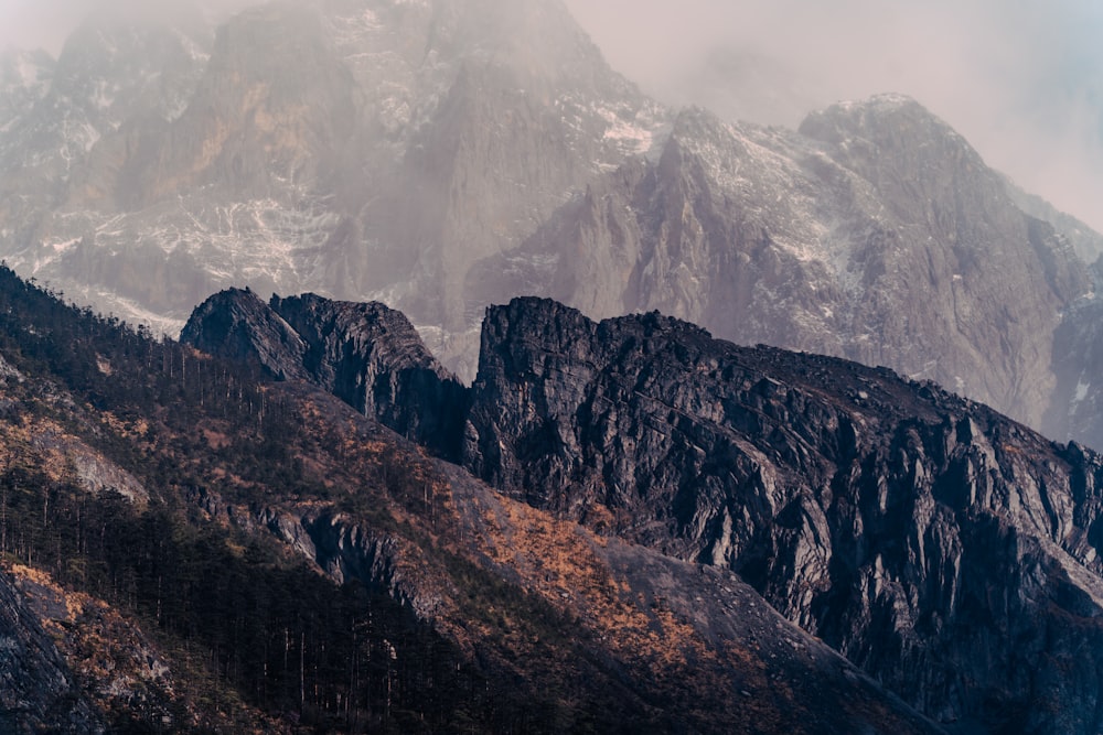 a mountain range covered in snow and brown grass