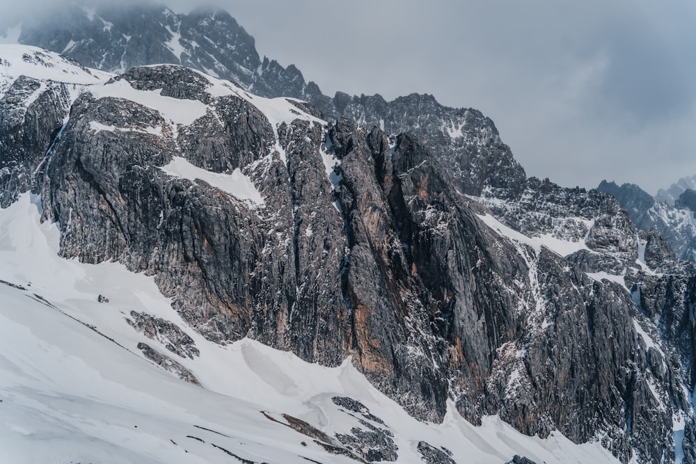 a large mountain covered in snow under a cloudy sky