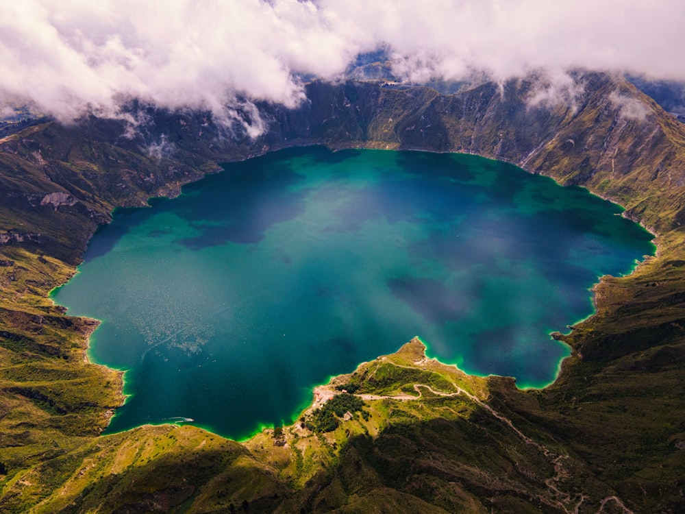 a large blue lake surrounded by mountains under a cloudy sky