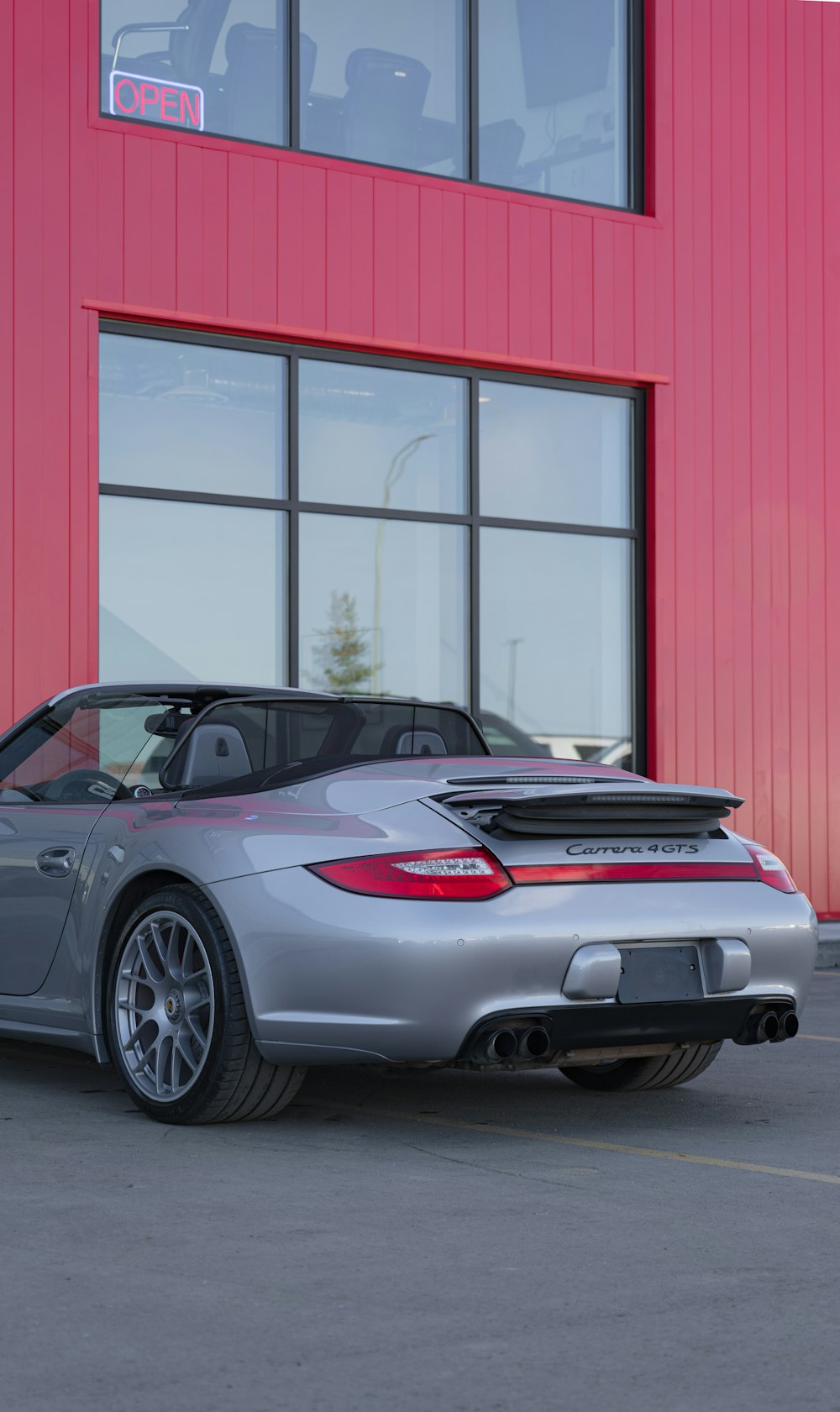 a silver sports car parked in front of a red building