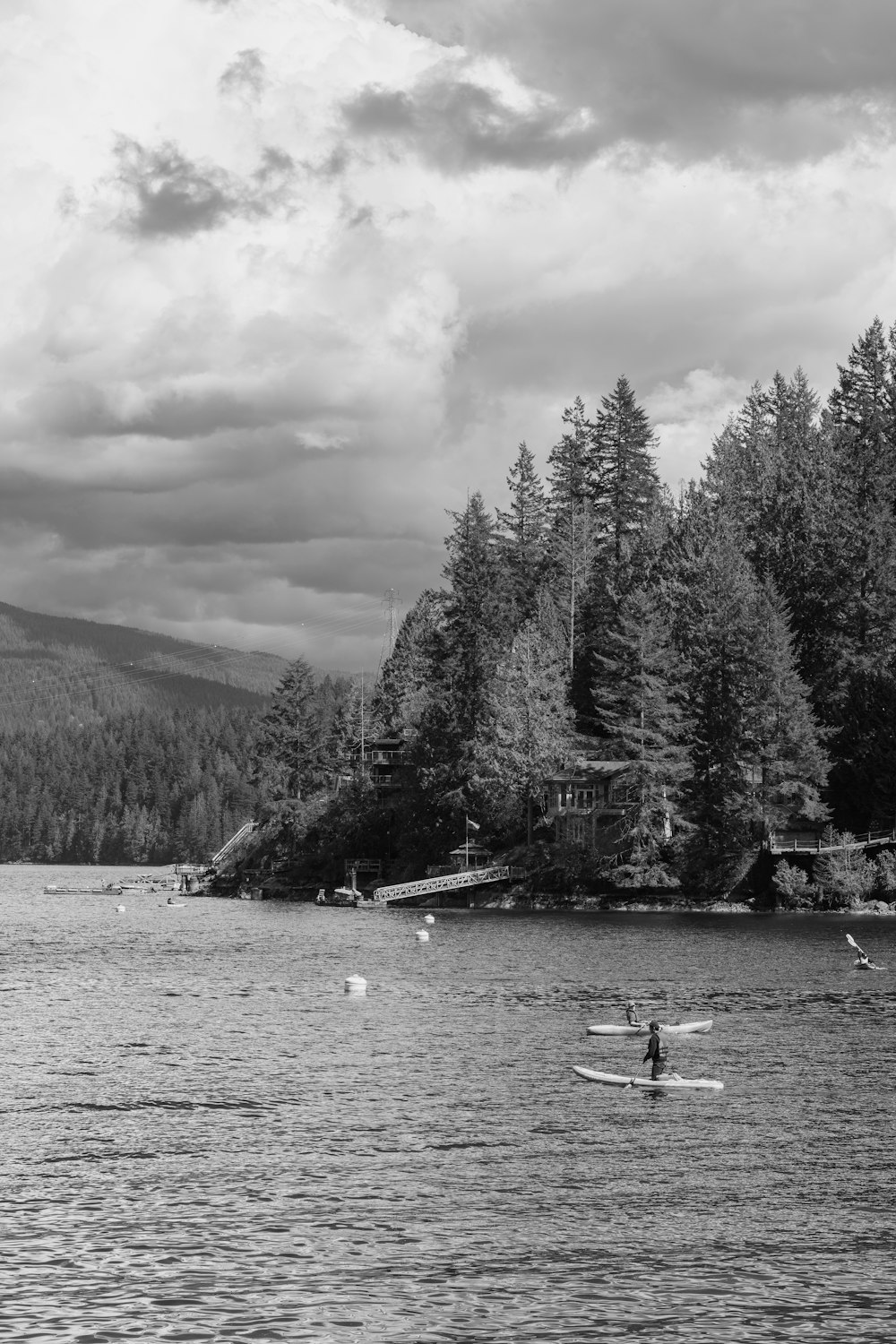 a black and white photo of a lake with people in it