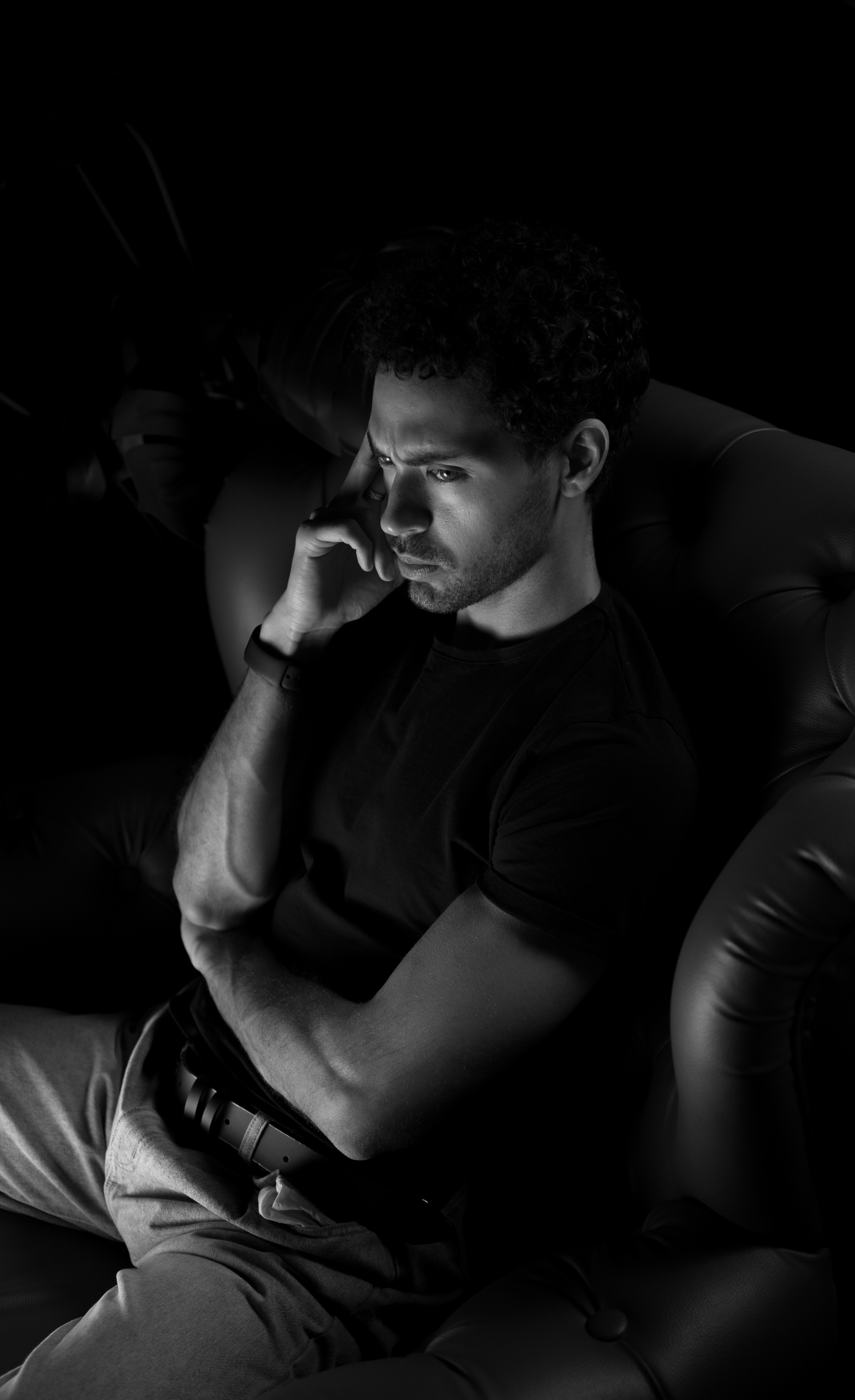 un homme assis sur une chaise en train de parler au téléphone portable