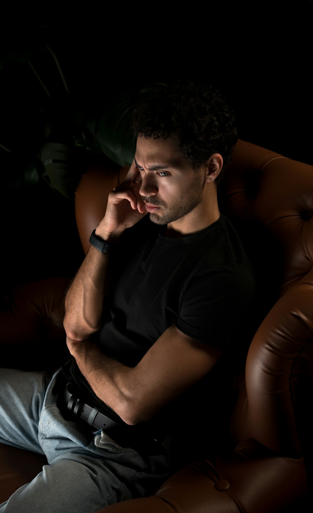 a man sitting in a chair with his hand on his chin